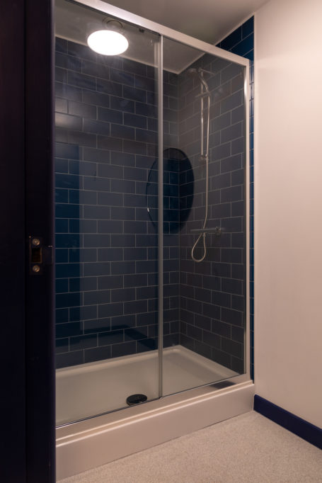 shower with blue tiles and glass door